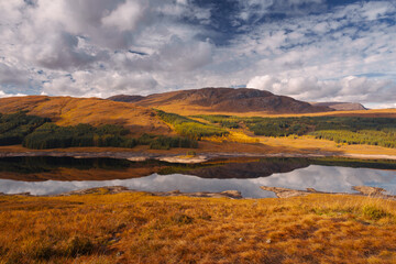 Golden heather blankets the Scottish Highlands, where misty peaks rise above deep glens and serene lochs. Autumn’s glow paints a landscape of wild, untamed beauty.