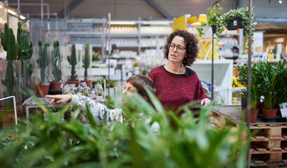 Woman and boy exploring indoor plant section at garden store