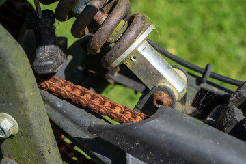 A rusty chain is attached to a bike. The chain is old and worn, and it is attached to the bike's rear end