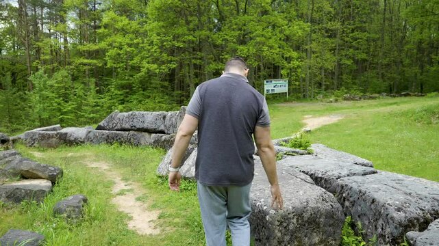 A lone tourist touching the scattered ancient rocks in the archaeological site of Mishkova Niva tomb located in Golyamo Gradishte Peak in Strandzha Mountain, Bulgaria.