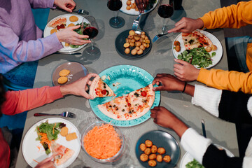 Friends sharing pizza and side dishes at dinner table