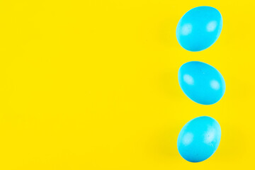 Three blue easter eggs on vivid yellow background with copy space make vibrant catch eye easter banner