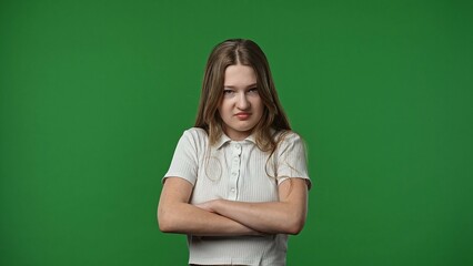 Teenage girl posing at camera with crossed arms and mad upset frustrated face, negative expression,...