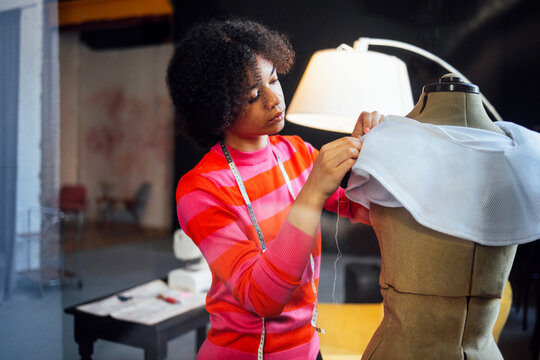 A young African stands next to a dressmaker mannequin - Powered by Adobe