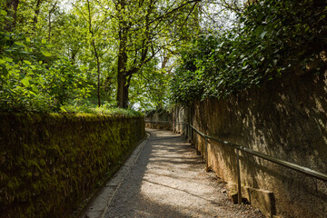 A path through a lush green Ljubljana's garden/park with stone walls