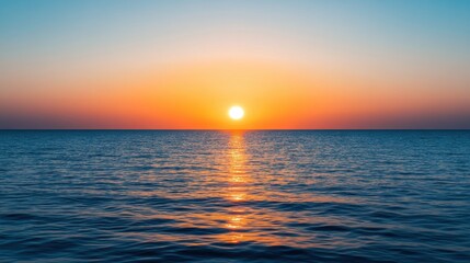 Obraz premium A stunning sunset over the ocean, with vibrant hues of orange and blue reflecting on the calm water surface.