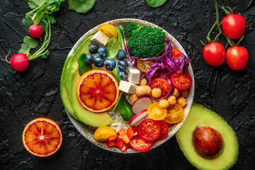 Buddha Bowl. Rainbow salad. Vegan poke bowl with avocado. Healthy food. Overhead flat lay shot with ingredients on a black background