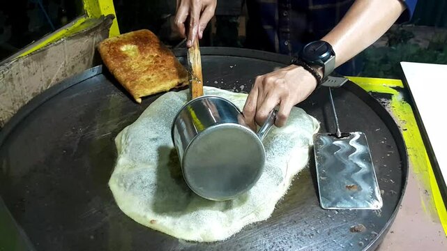 Egg martabak is being made on a hot flat pan. Martabak is a typical Indonesian food.