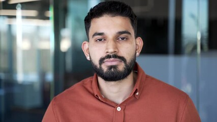 Portrait of serious businessman standing at workplace in modern glass business office. Head shot of confident focused successful entrepreneur looking at camera. Handsome manager in workspace. Close up