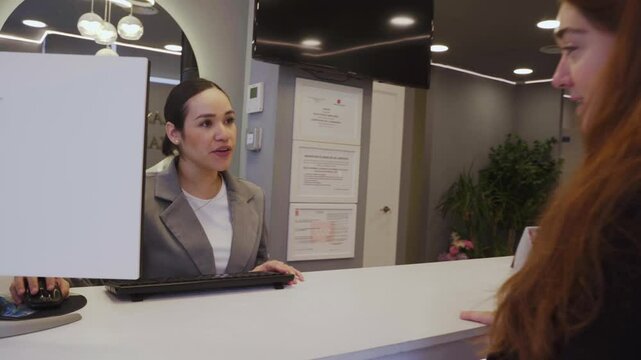 Patient entering dental clinic and talking to receptionist