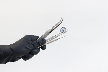 Dental instrument in the hands of a dentist, close-up. Dental mirror, tweezers and hooks used in the treatment of various diseases of the teeth and gums. Diagnostic dental instrument set