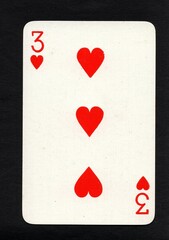 A vintage three of hearts playing card on a black background.