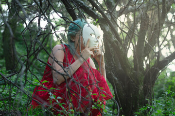 face of a woman hidden behind a white mask in a forest