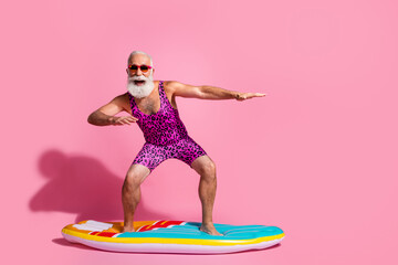 Photo of positive crazy grandfather wear swimsuit resort surfing wave sport isolated on pink color...