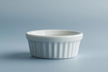 A small white ceramic ramekin is displayed on a blue background