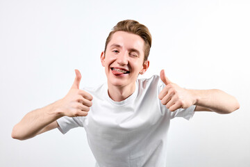 A man is shown wearing a white shirt, actively giving a thumbs up gesture. His expression is...