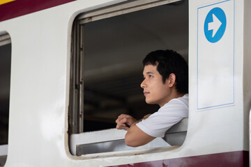 Reflective Journey and Travel Anticipation. A young man gazing thoughtfully out of a train window,...