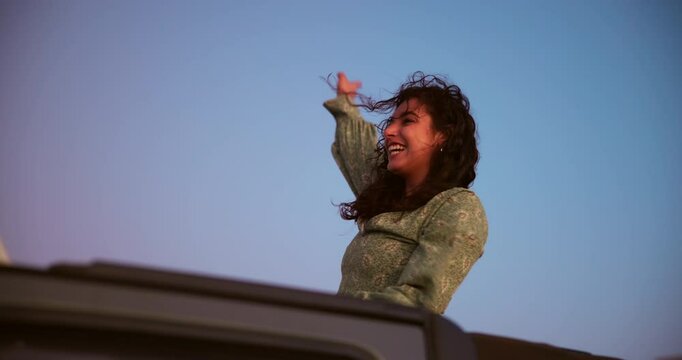 Travel, freedom and woman with celebration in car for holiday break, fresh air or summer journey. Vacation, excited girl and road trip with sunroof for outdoor breeze, dancing or adventure in vehicle