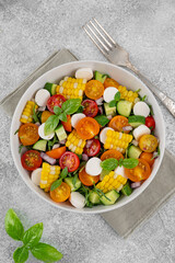 Sweet corn salad with arugula, tomatoes, cucumber, red onion and mozzarella. Healthy food. Top view.