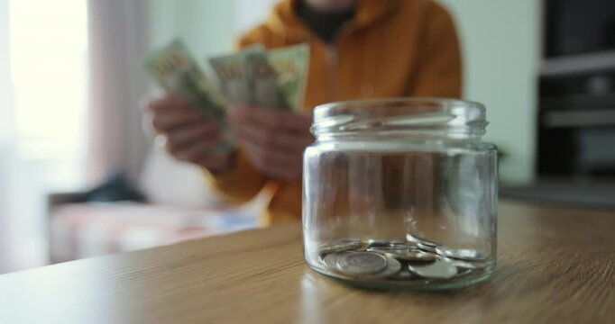 Man putting a roll of money in a glass jar. Family saving money. Money box.Family saving money.