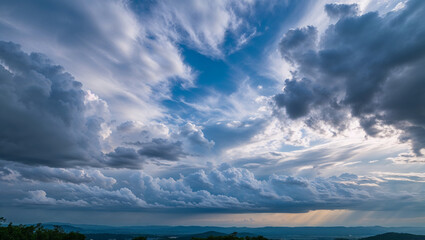 Obraz premium Dramatic cloudscape forming over valley at sunset with sunbeams