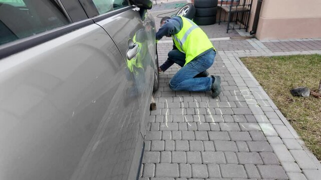 A guy changes tire on street to summer tire in nature