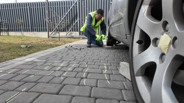 A guy changes tire on street to summer tire in nature