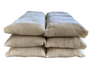 Relaxing linen eye pillows stacked near a window overlooking a tranquil landscape.  Perfect for spa, wellness, and mindfulness imagery evokes serenity, calm, and natural comfort.