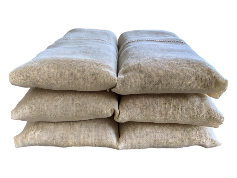 Relaxing linen eye pillows stacked near a window overlooking a tranquil landscape.  Perfect for spa, wellness, and mindfulness imagery evokes serenity, calm, and natural comfort.