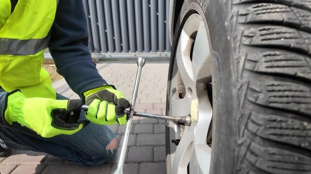 A guy changes tire on street to summer tire in nature