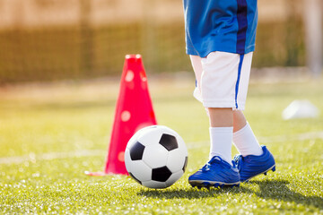 Legs of Little Child with Soccer Ball. Soccer Ball and Pylons on Grass. Youth Soccer Player...