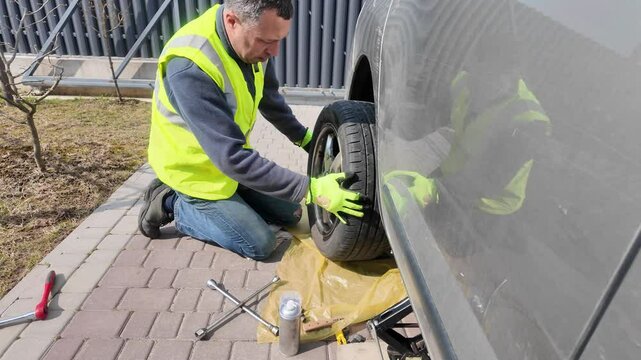 A guy changes tire on street to summer tire in nature