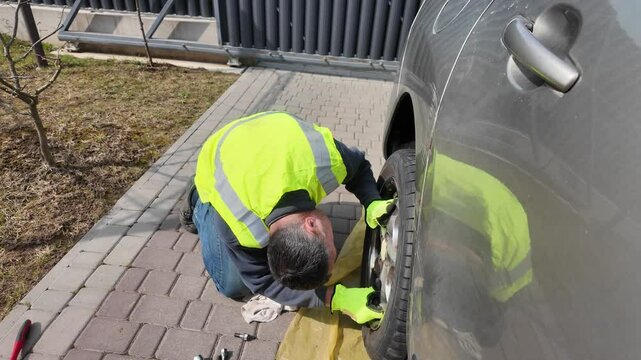 A guy changes tire on street to summer tire in nature