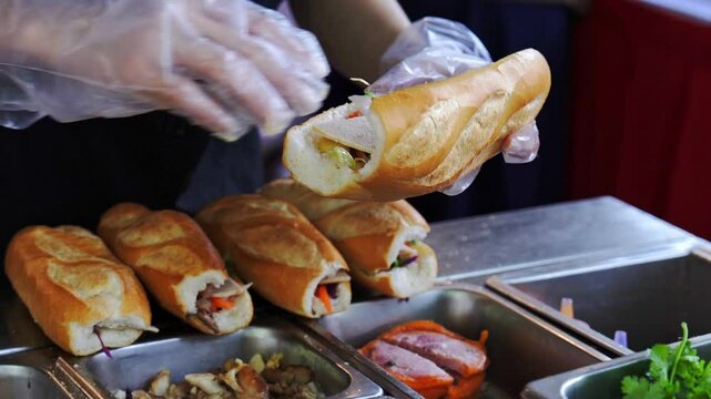 Female chef serving traditional vietnamese sandwich Banh Mi in street food with meats, pork roll and vegetables. It combines Vietnamese cuisine with French condiments like pate