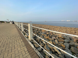 Obraz premium Beach with rock fragments and blue sky background with rope barrier