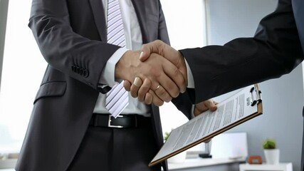 Business partners handshake with each other symbolizing teamwork cooperation. Two male professionals shaking hands after sealing deal in large office building. Concept of partnership among colleagues