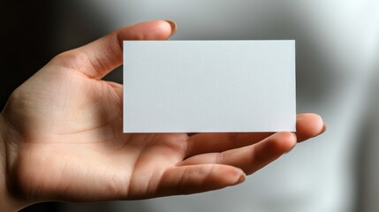 Fototapeta premium An open hand holding a blank business card, modern and unique, set against a clean white background.