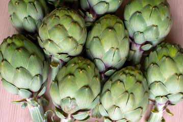 Obraz premium A detailed view of multiple green artichokes laid out on a table showcasing their texture. The image highlights the fresh, natural appearance of these vegetables, ideal for culinary, food, diet