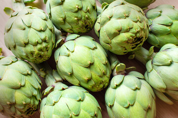 Obraz premium A detailed view of multiple green artichokes laid out on a table showcasing their texture. The image highlights the fresh, natural appearance of these vegetables, ideal for culinary, food, diet