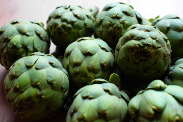 Fototapeta premium A detailed view of multiple green artichokes laid out on a table showcasing their texture. The image highlights the fresh, natural appearance of these vegetables, ideal for culinary, food, diet