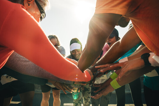 Group of runners huddling with hands united before a race