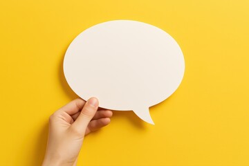 Hand Holding Blank Speech Bubble on Bright Yellow Background Offering Customizable Messaging