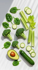 Composition of leafy greens with broccoli, avocado and courgette on a light background with natural light. Healthy diet concept, recipe for detox and vegetarian dish