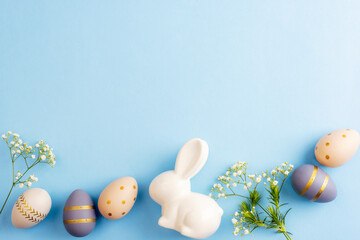 Easter eggs, flowers and ceramic bunny on blue background. Easter concept. Top view, flat lay, copy space