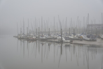 Boats moore in marina on River Arun at Littlehampton in West Sussex, England, calm and misty.