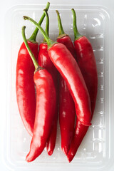 Close up Texture of Vibrant Red Chili Peppers in a Plastic Container on White and Isolated Background