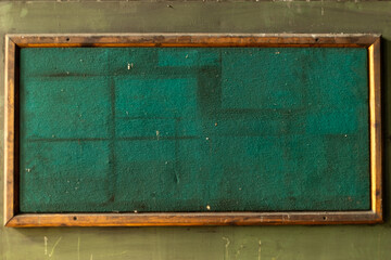 A detailed shot of the textured green surface of an old notice board. The image focuses on the worn and aged fabric, highlighting its vintage character.