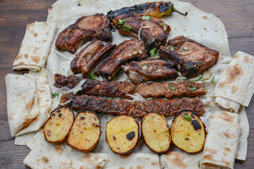 Barbecue with grilled meat and shish kebab. Grilled lamb ribs, kebab, potatoes and pita bread on wooden board. Restaurant food, pork barbecue, bbq.