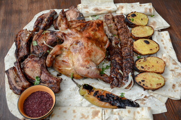 Grilled chicken with potatoes and pork barbecue on the table. Pork and chicken barbecue wrapped in pita bread. Roasted chicken and meat bbq
