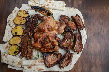 Grilled chicken with potatoes and pork barbecue on the table. Pork and chicken barbecue wrapped in pita bread. Roasted chicken and meat bbq